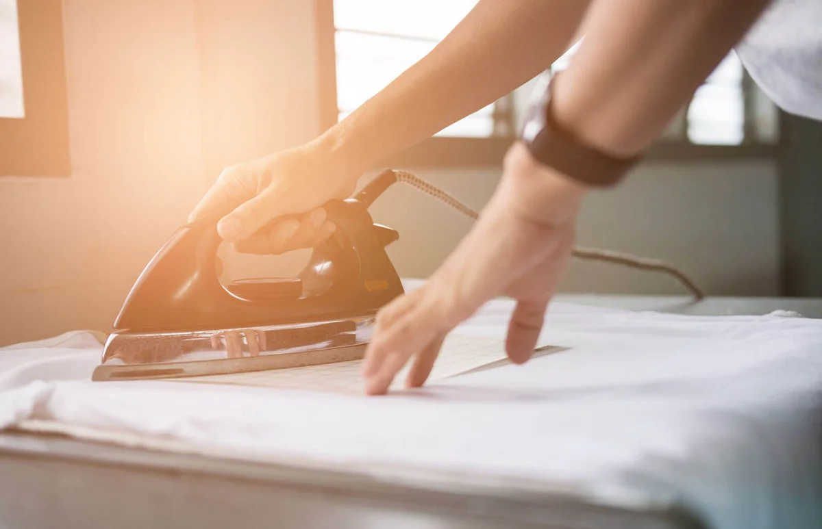 woman ironing waterproof film on fabric at shop