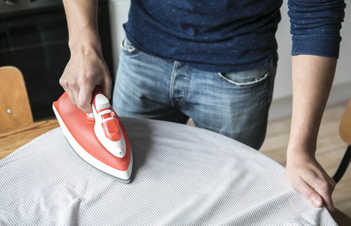man ironing shirt on table at kitchen
