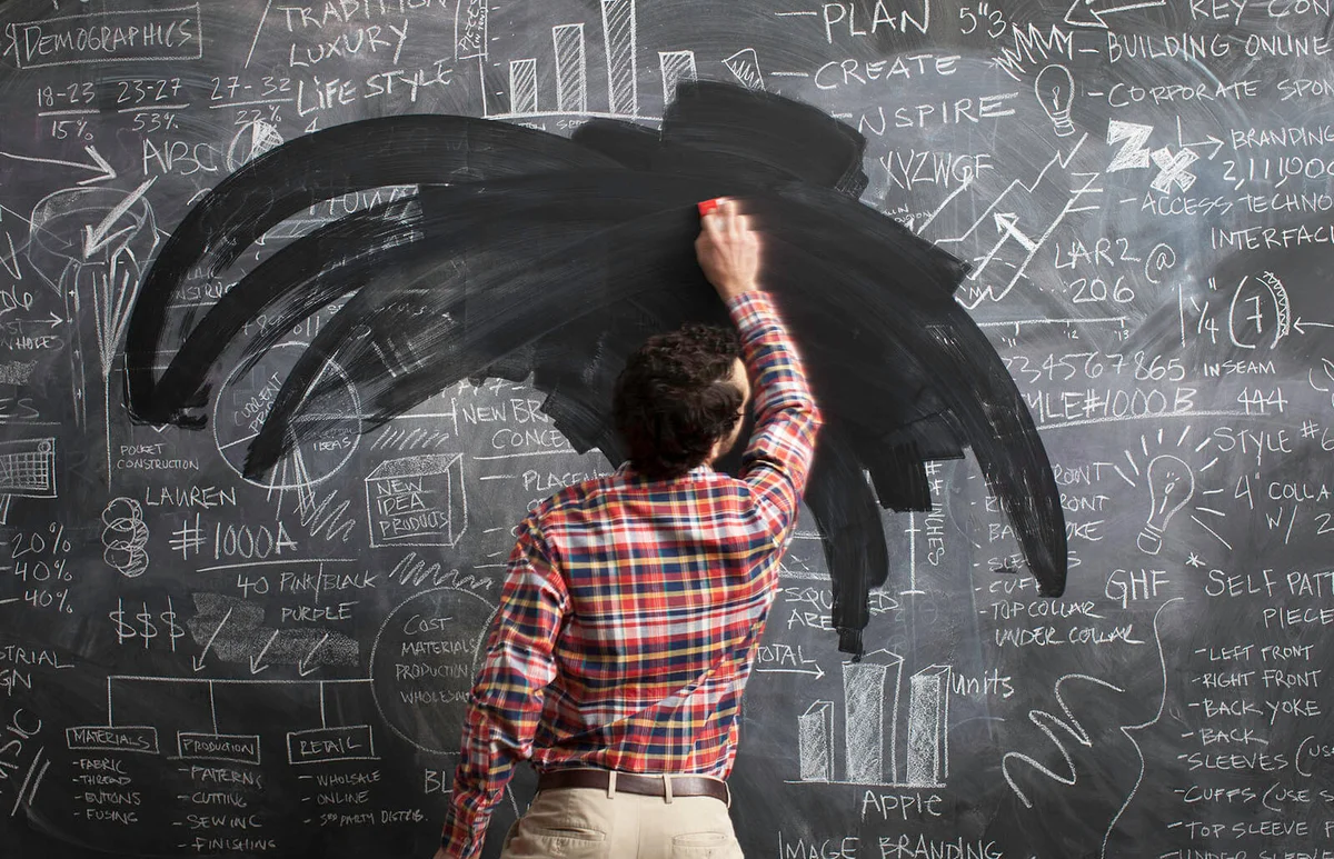 male erasing business plans on blackboard