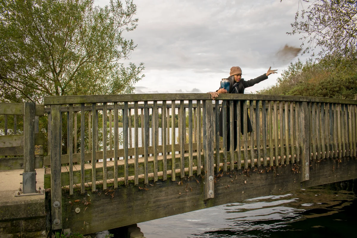 woman scattering cremated ashes off bridge into water