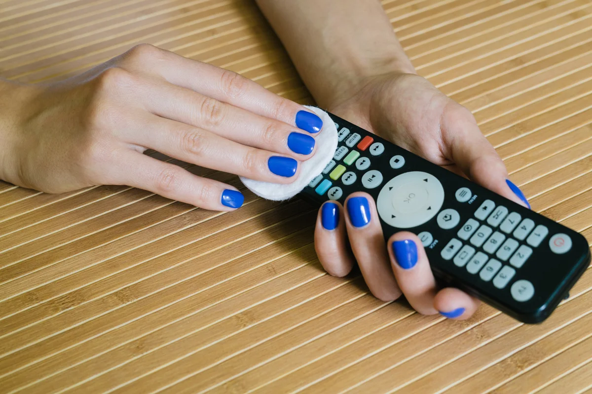 woman cleaning a remote control with a pad