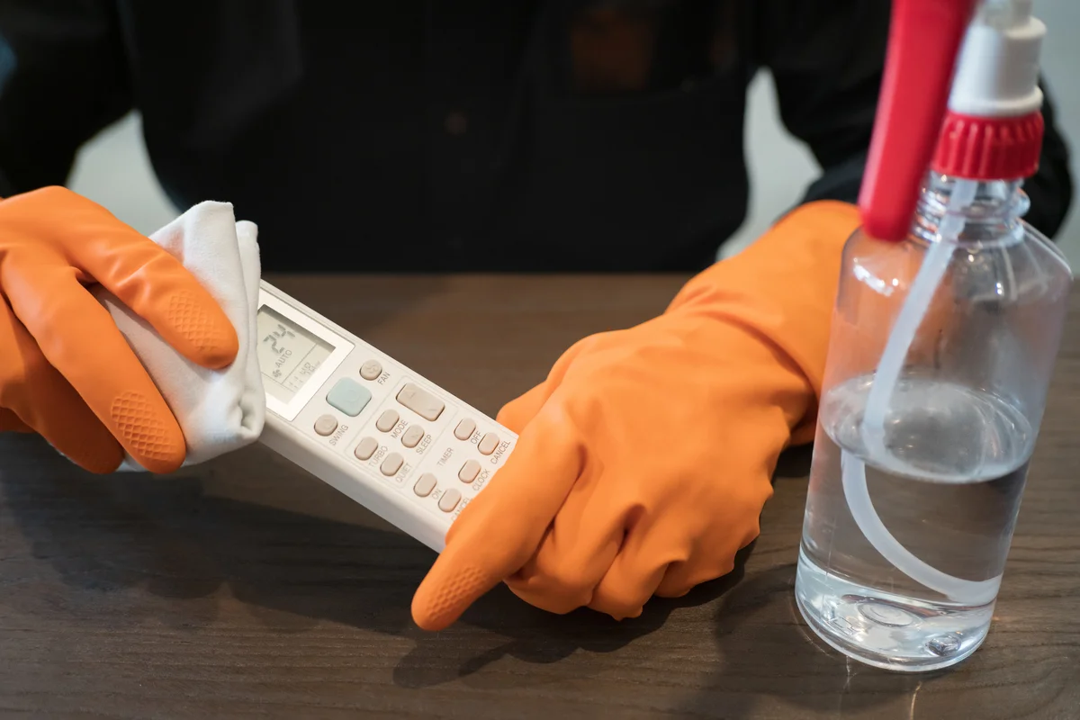 woman wearing rubber gloves cleaning remote