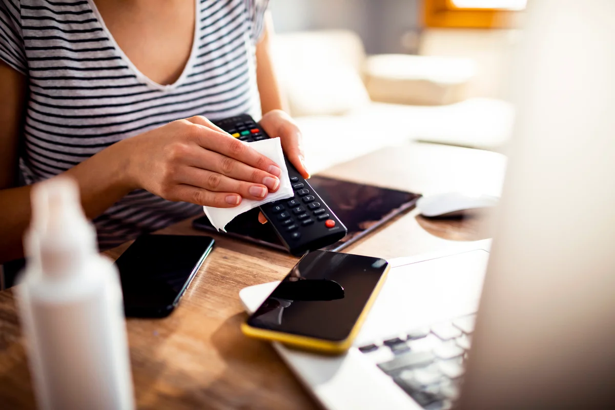 woman cleaning and disinfecting TV remote control
