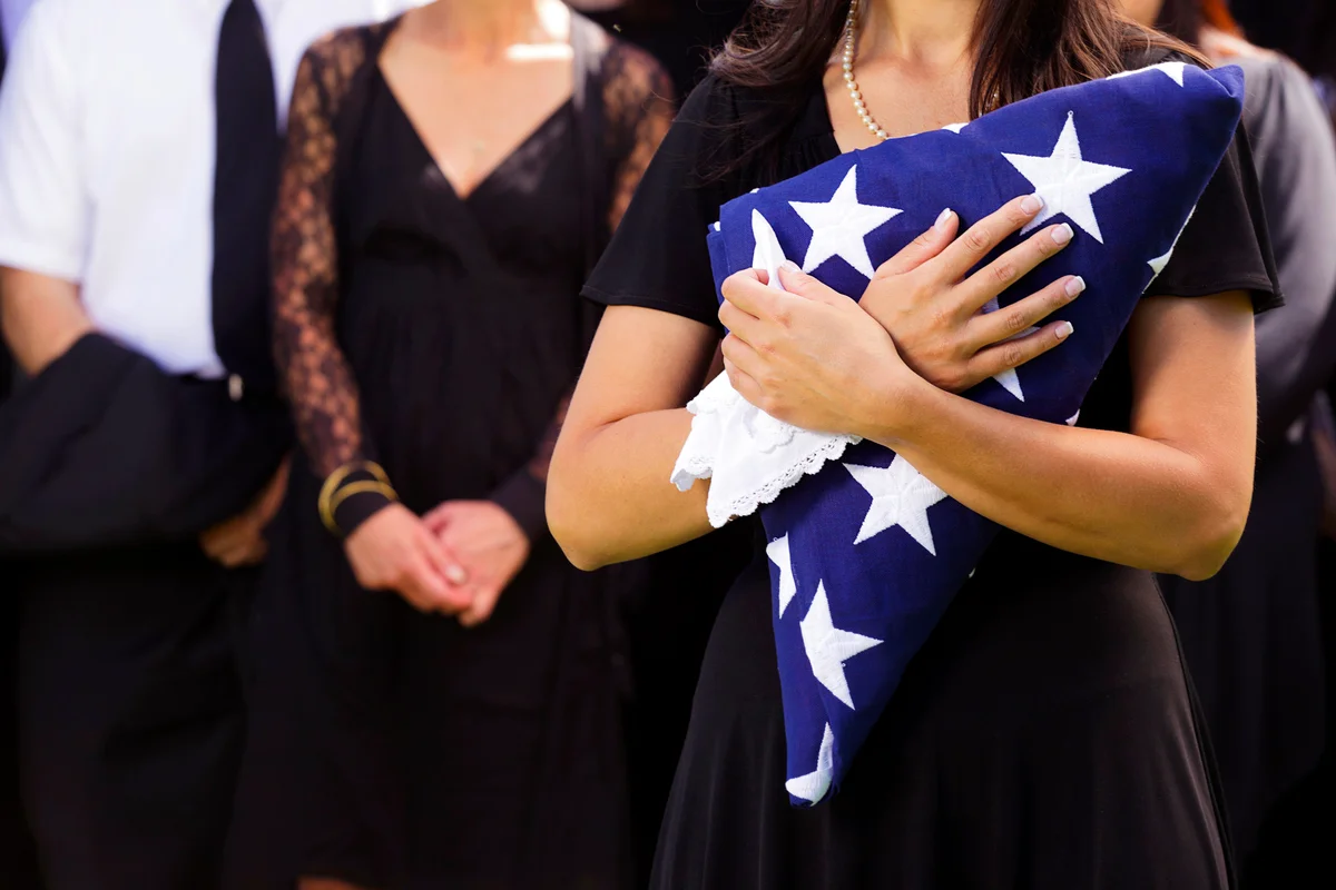 Woman holding a folded American flag at a funeral