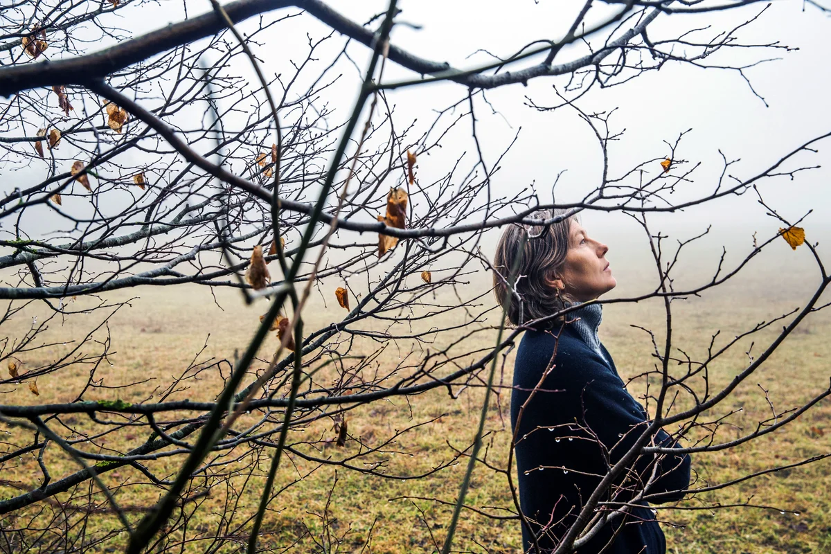 Sad middle age woman walking in winter forest