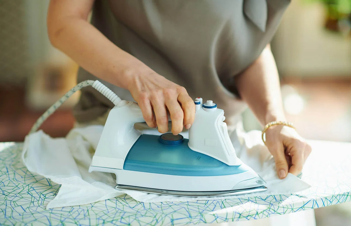 woman in house in sunny day ironing on board