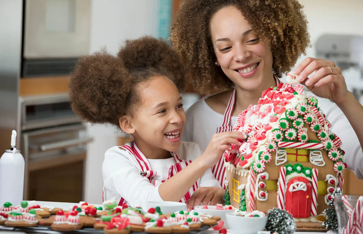 mother and daughter decorating gingerbread house