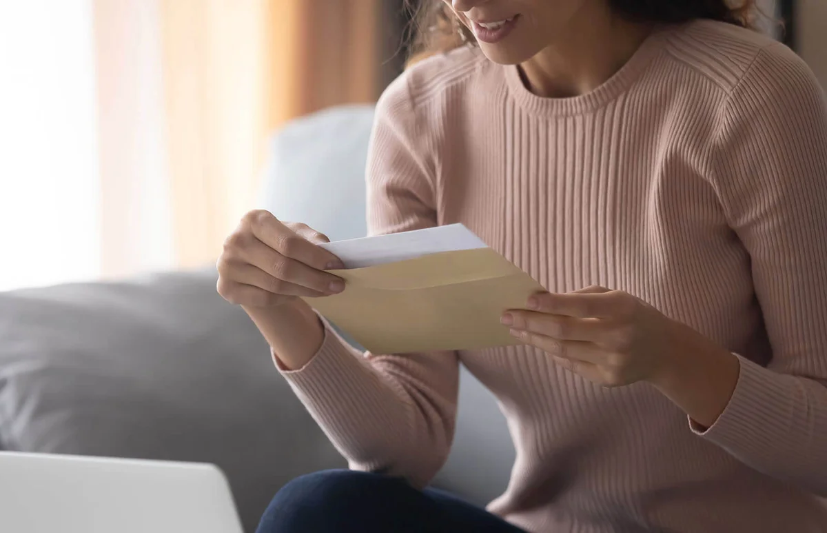 Smiling young woman holding envelope with paper letter