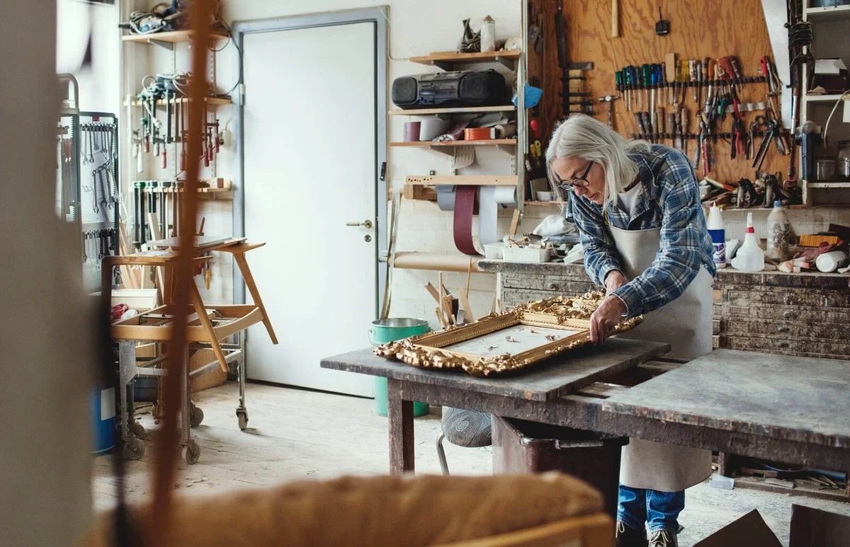 Senior female owner working on carved product at workshop