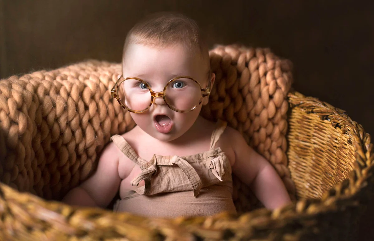 cute funny baby with eyeglasses sitting in a basket
