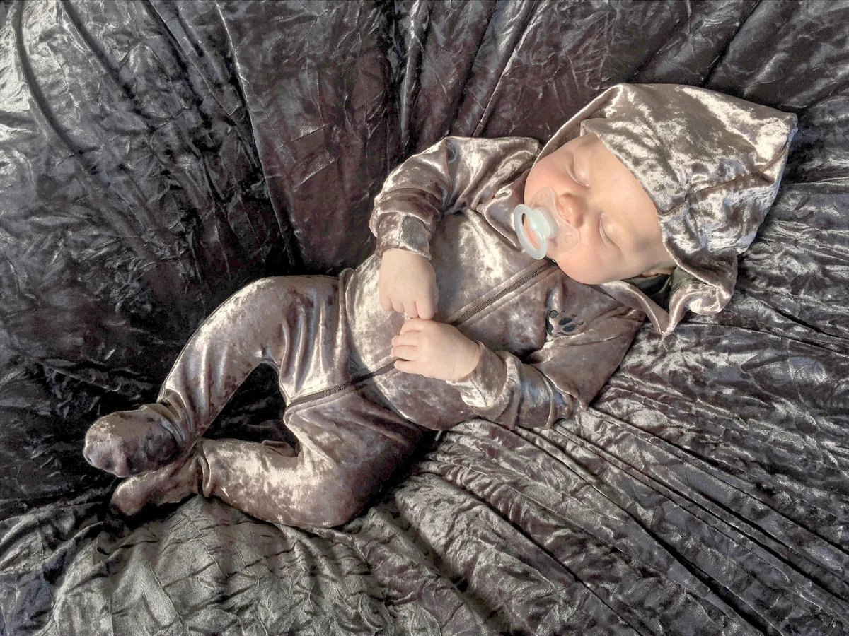 Infant wearing a shiny velour romper sleeping peacefully