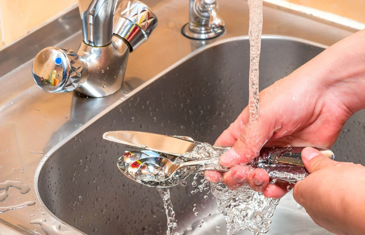 washing cutlery under running water in the kitchen