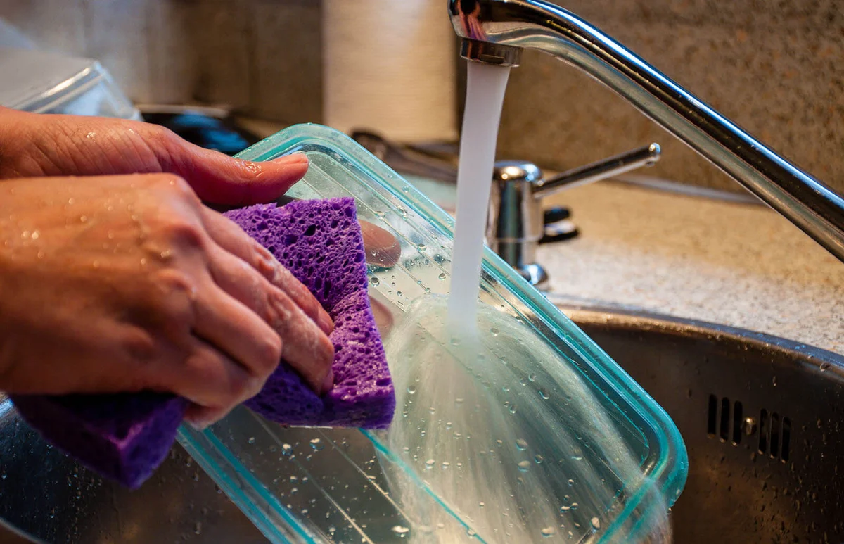 Woman washing a plastic food storage container