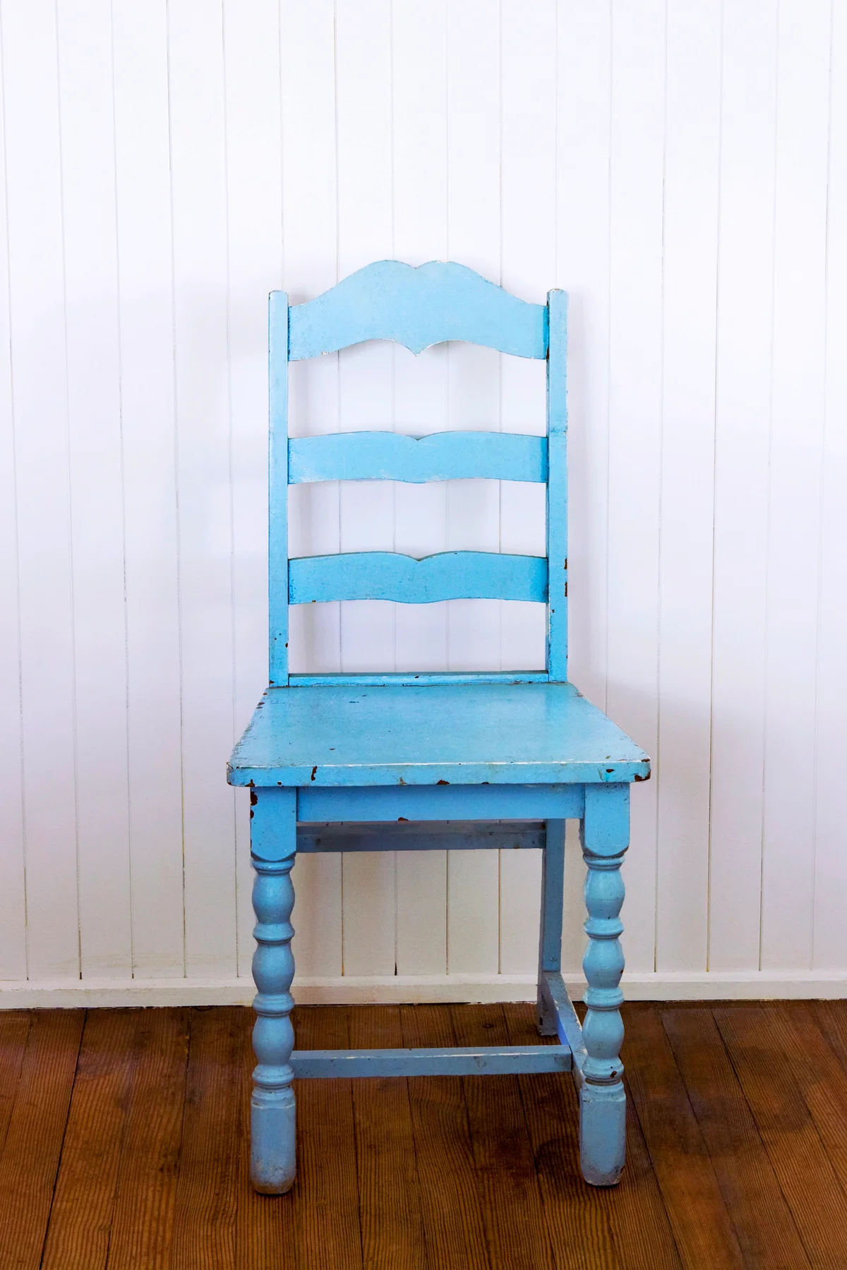 Old Blue Ladder Back Chair Against White Wall
