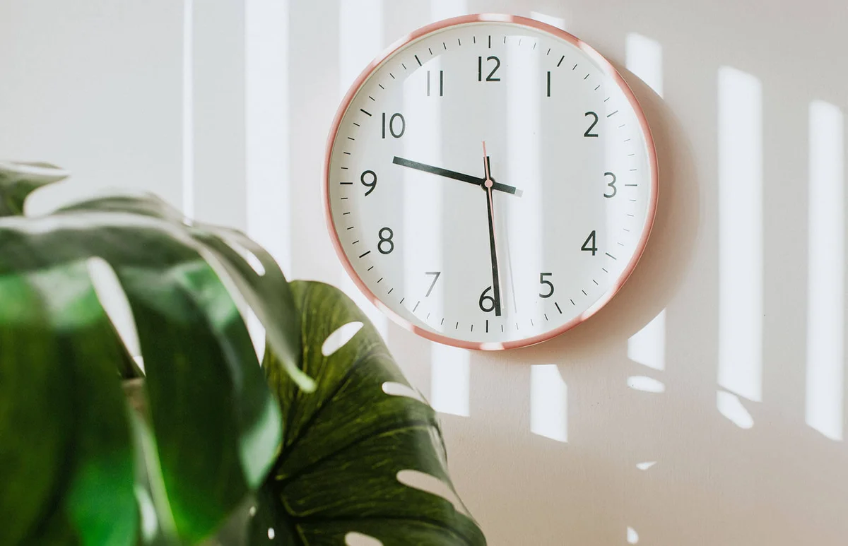 Pink clock hanging on a plain white wall