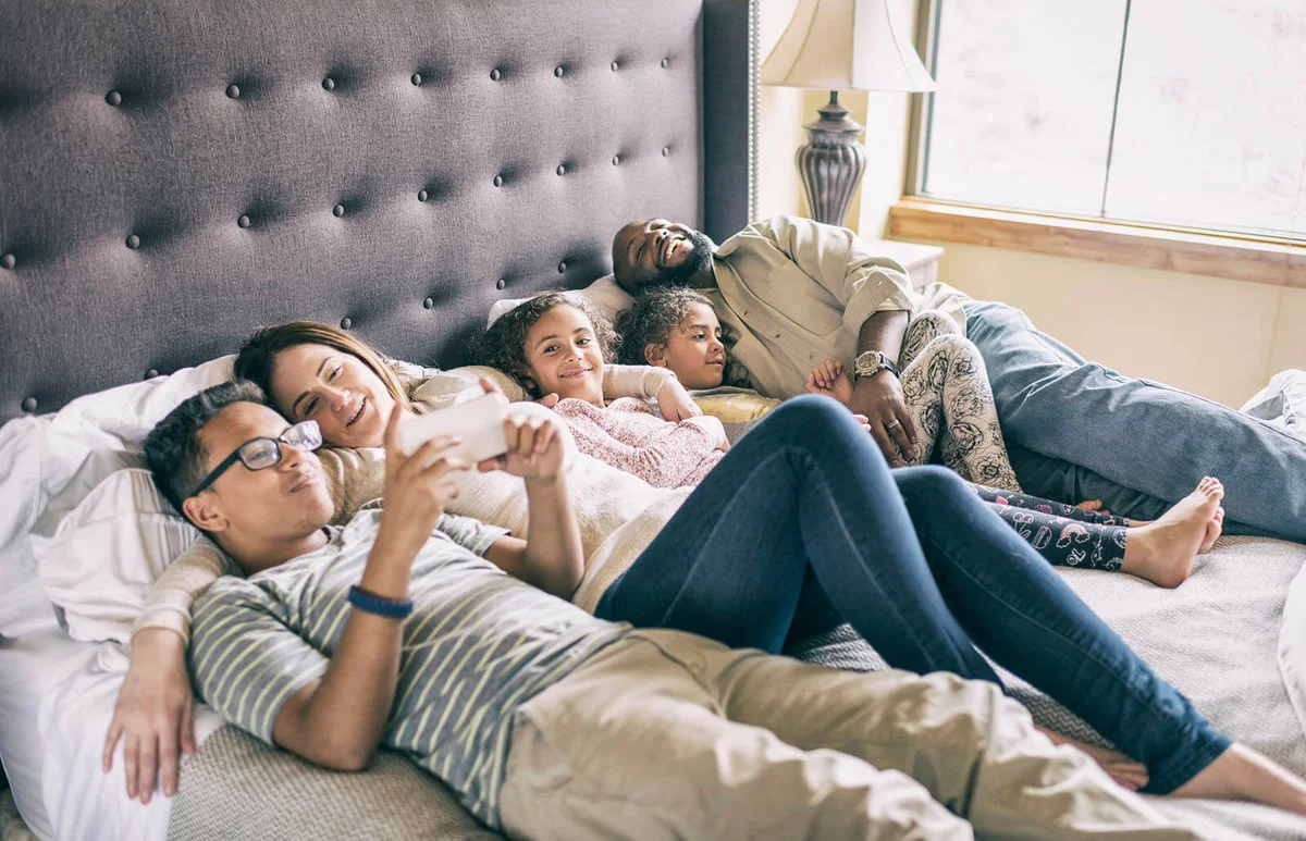 family relaxing on bed together during the day