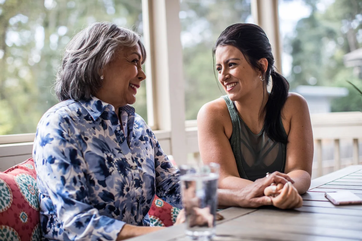 Senior woman and adult daughter laughing on porch