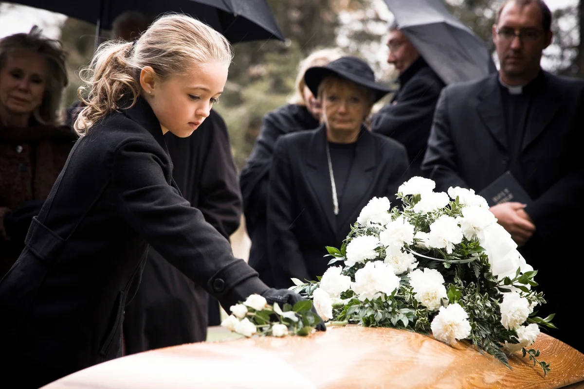 Little girl laying flowers on the coffin