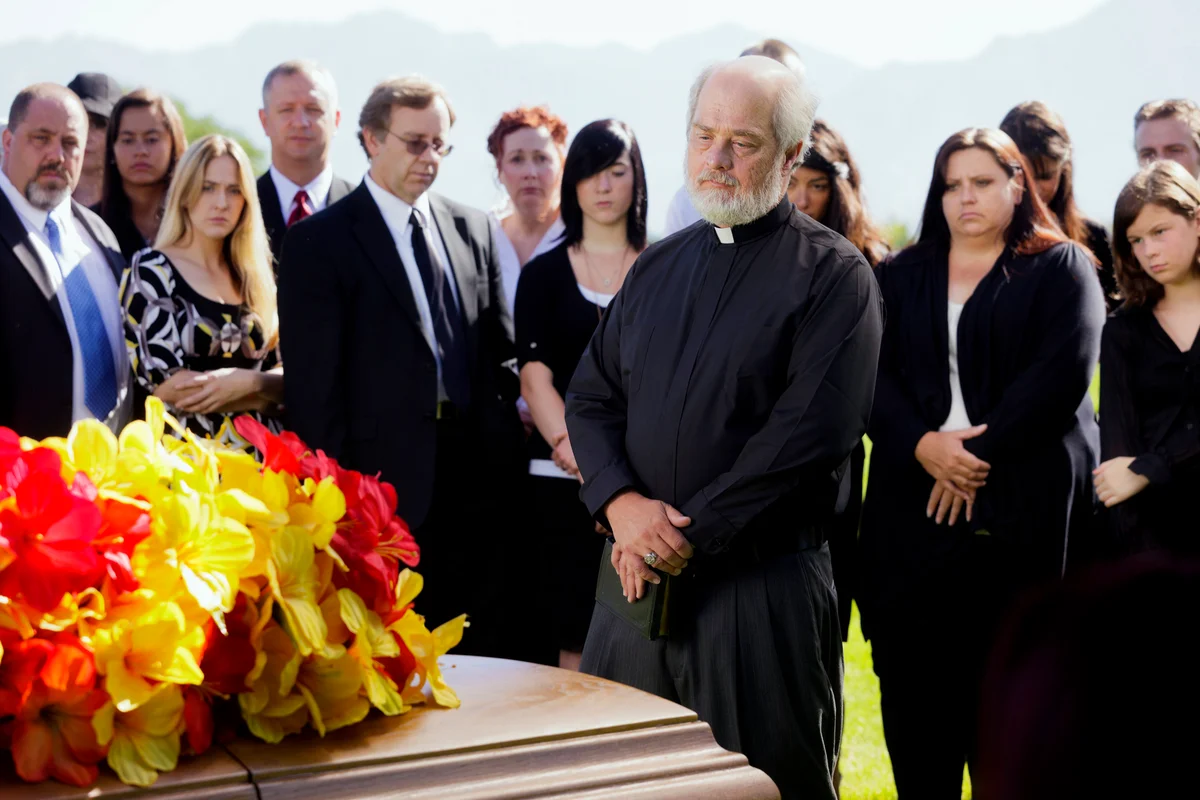 A priest standing graveside at a funeral