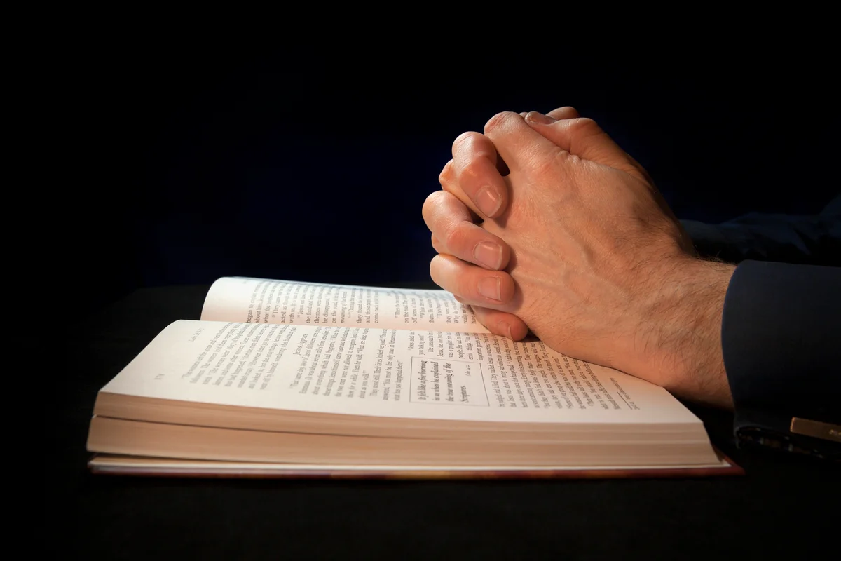 Clasped hands on a bible while praying