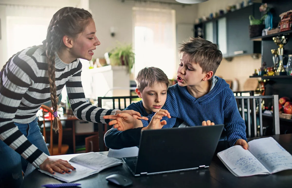 Three kids fighting for laptop at home