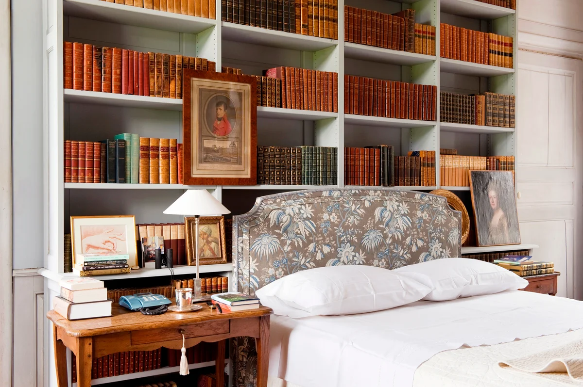 Bookshelves above a bed with a Marvic fabric headboard