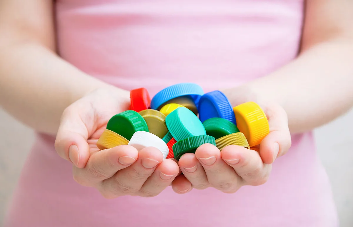 girl holding plastic caps