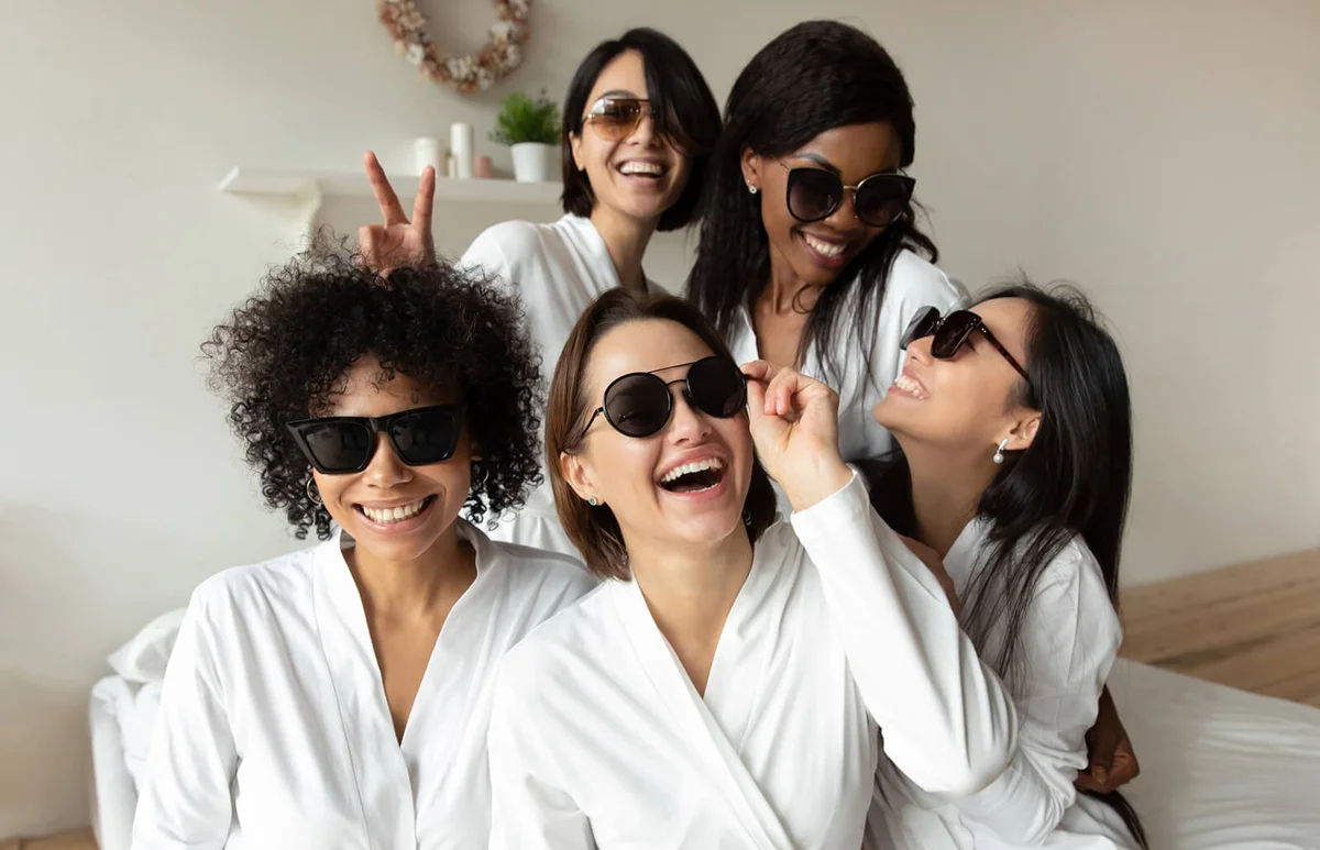 Cheerful young ladies laughing look at camera wear sunglasses bathrobes
