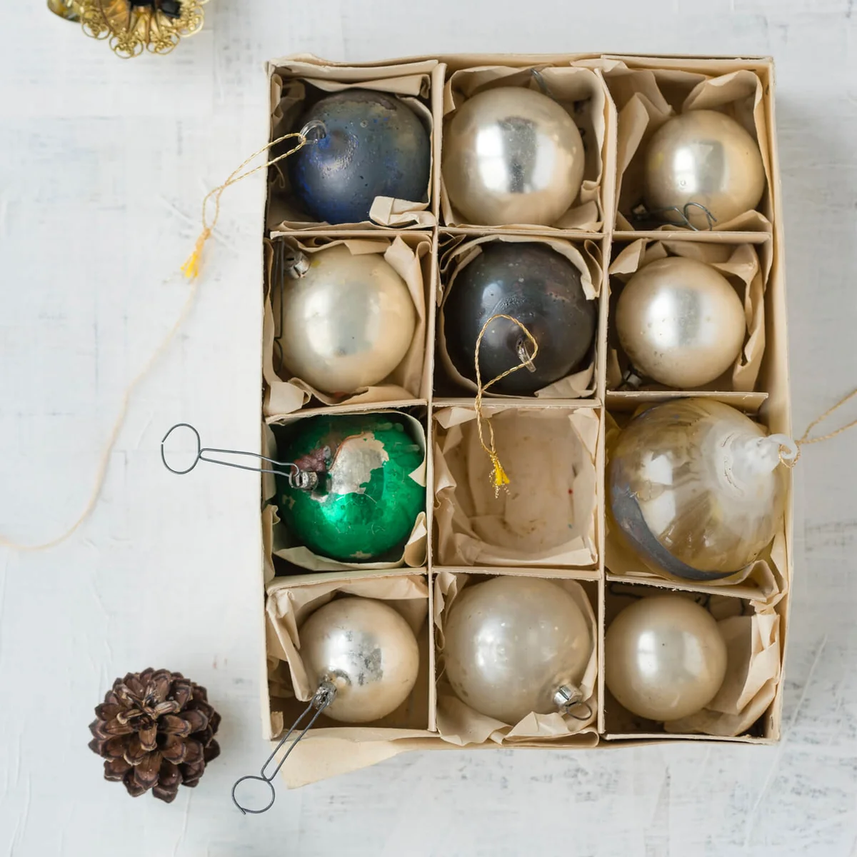 Cardboard box of old glass Christmas baubles on white ground
