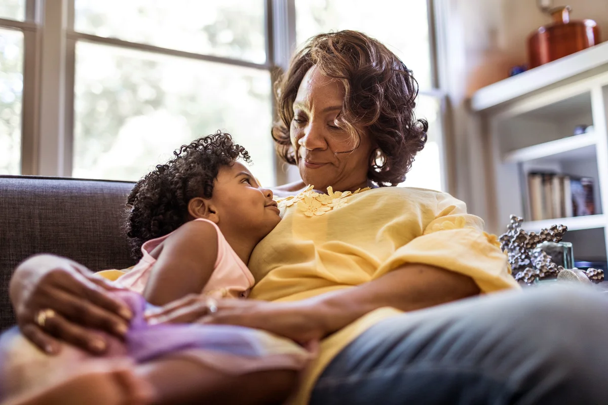 Grandmother and granddaughter cuddling on couch
