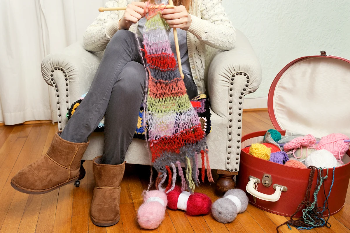 Woman knitting and using a vintage suitcase to store supplies