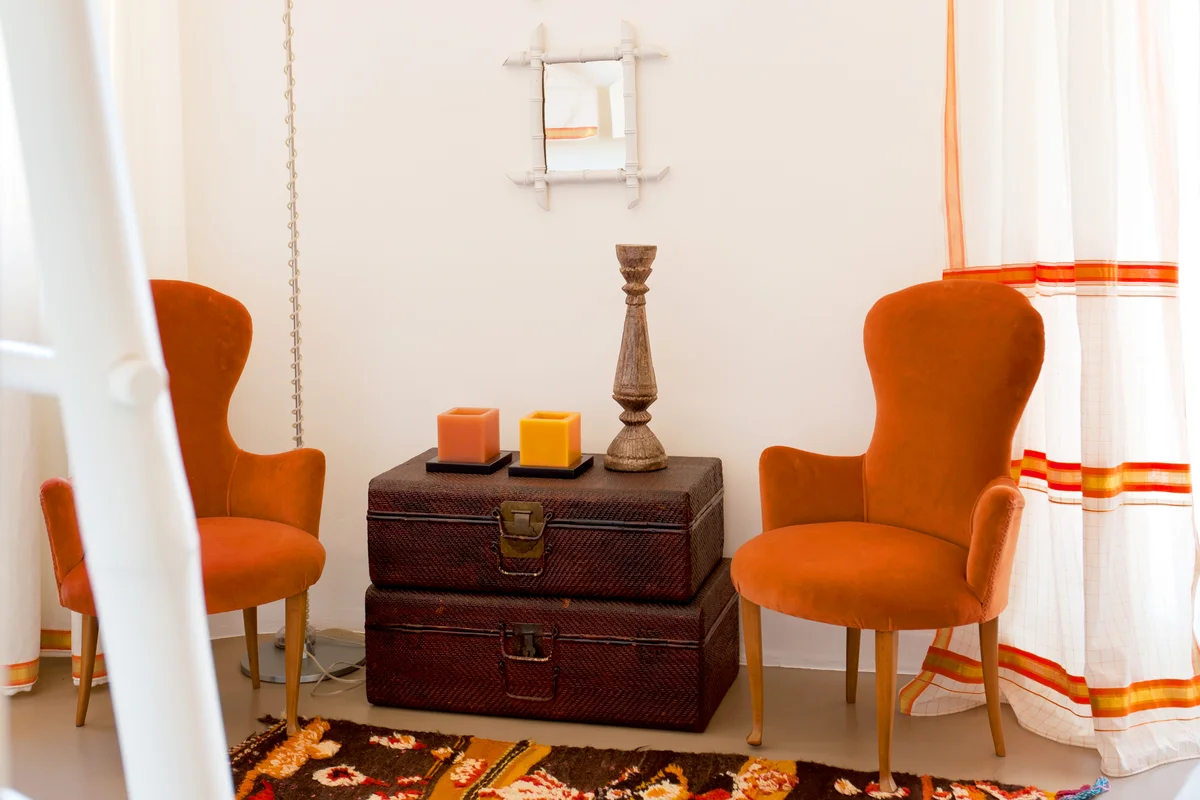 Italian chairs flank vintage trunks in room with Moroccan rug