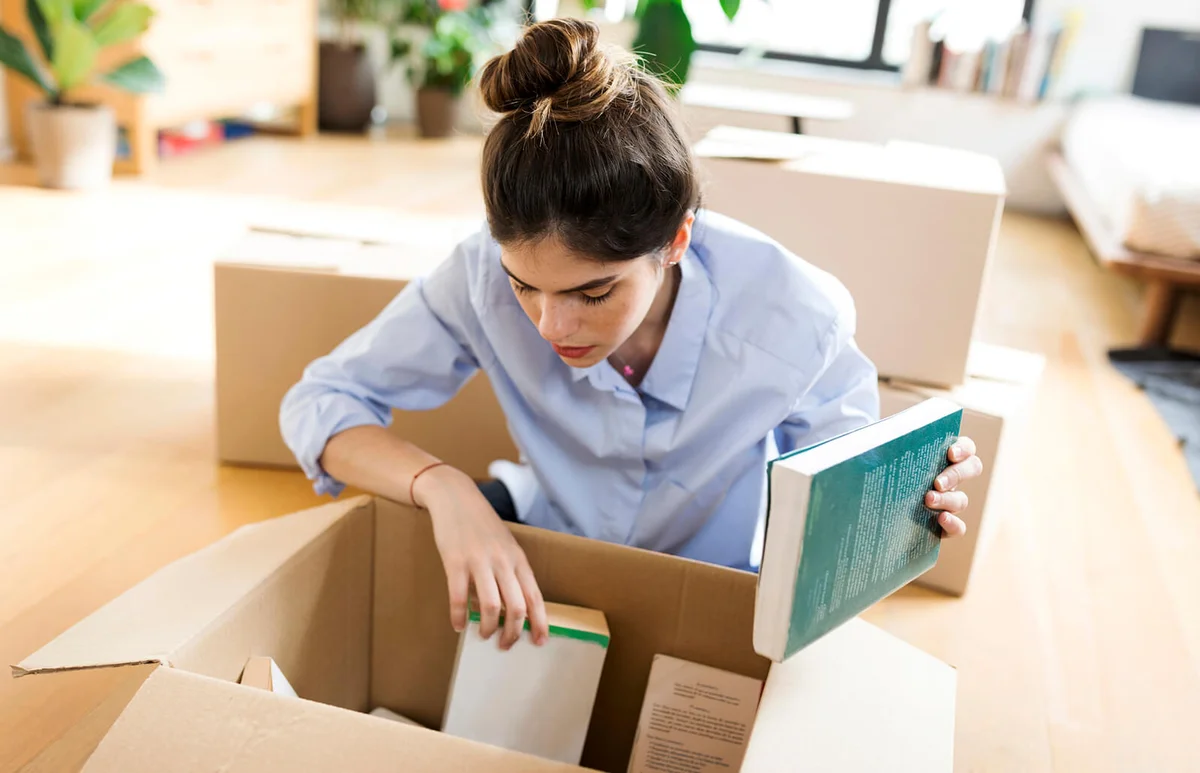 woman unpacking cardboard box in new apartment