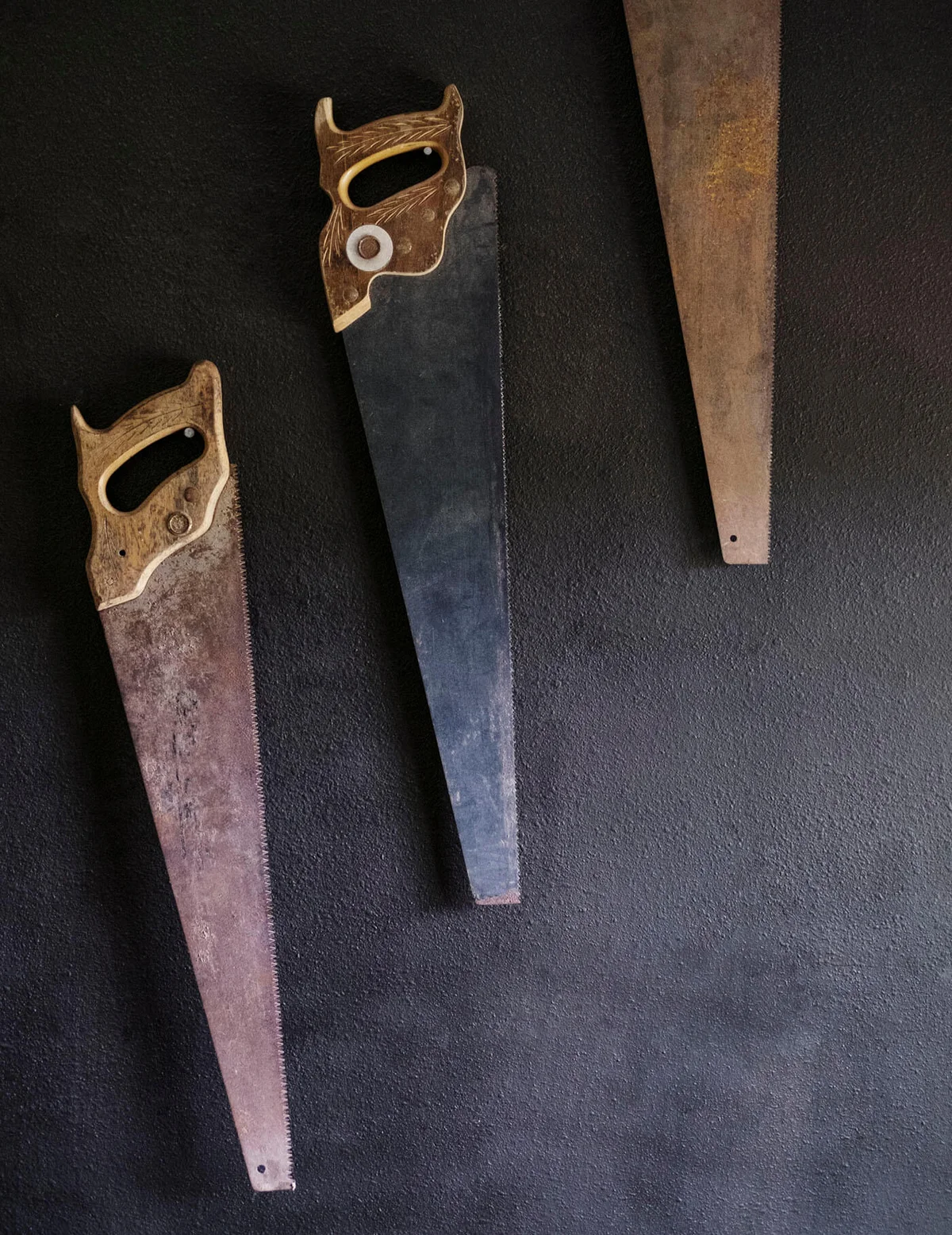 Old rusty hand saws hanging on wall