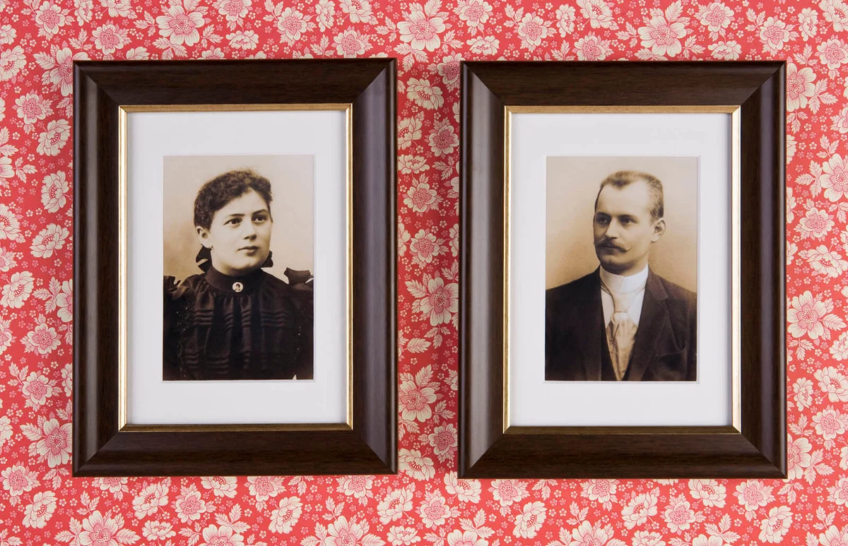 Two photographs hanging on a wallpapered wall