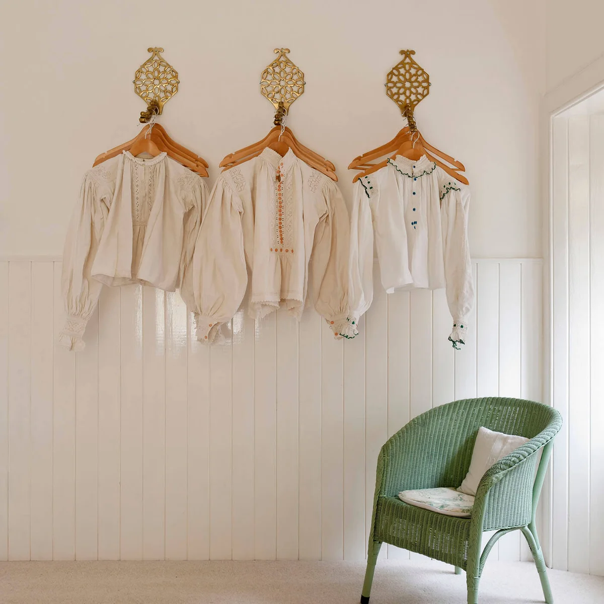 Antique Hungarian linen smocks and shirts hung decoratively on a white wall