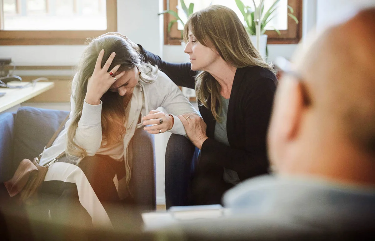 Mother consoles daughter during therapy session at workshop
