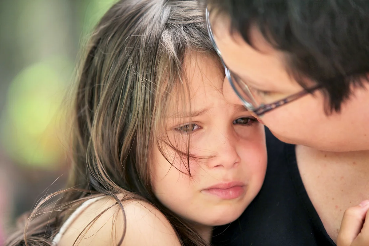 Mother comforting teary young girl