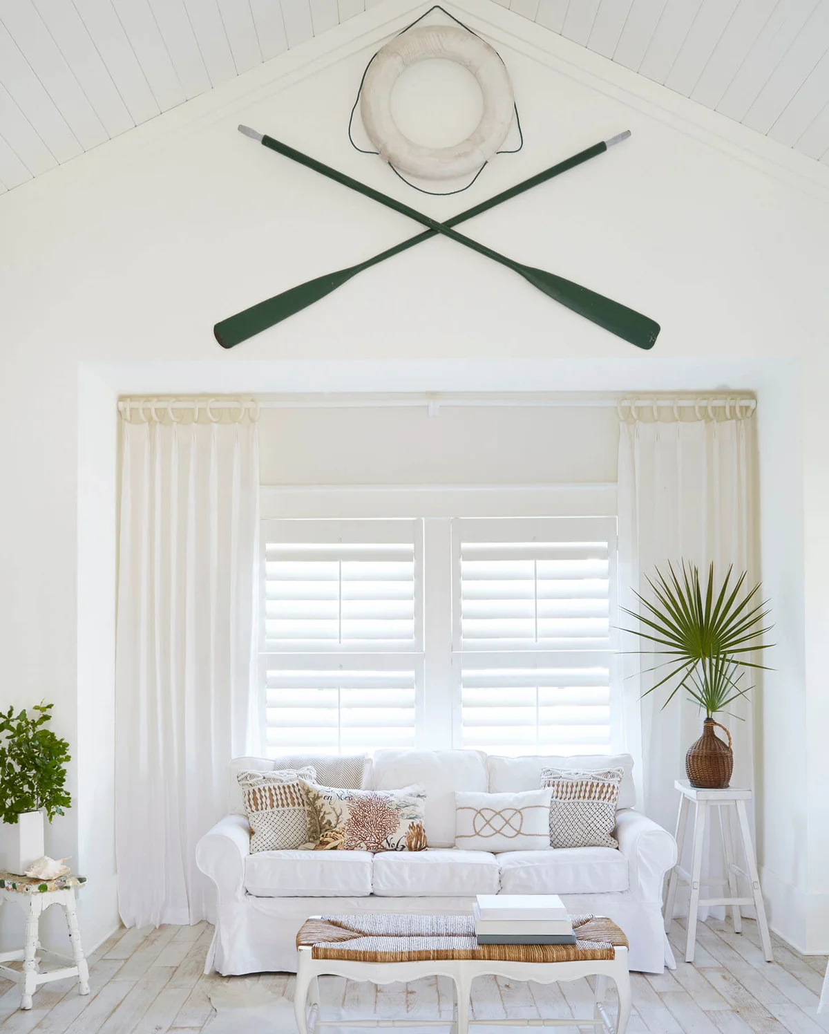 Oars and lifebelt hanging on wall above sofa at beach cottage