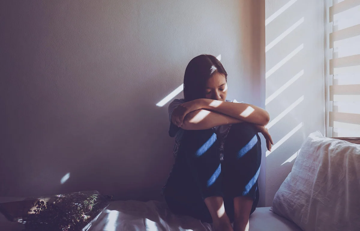 Sad woman sitting on bed at home