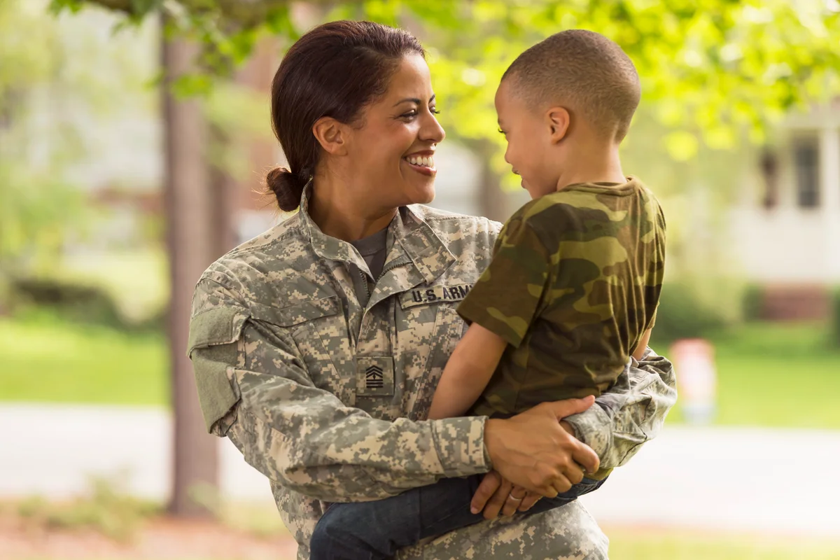 African American soldier mother carrying son