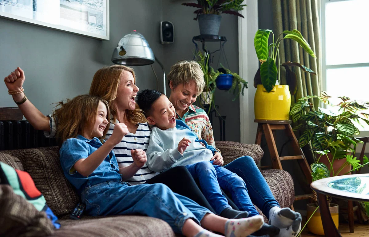 Cheerful family with two mums watching tv at home