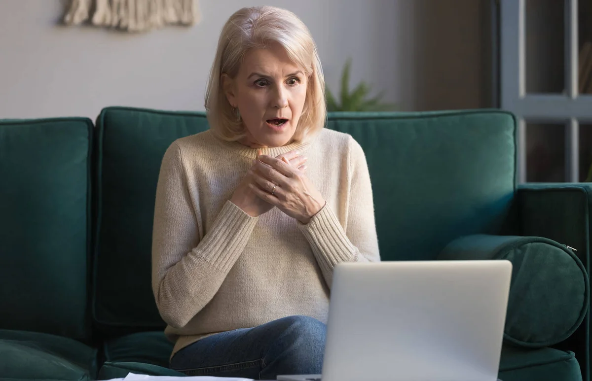 woman reading unexpected news on laptop