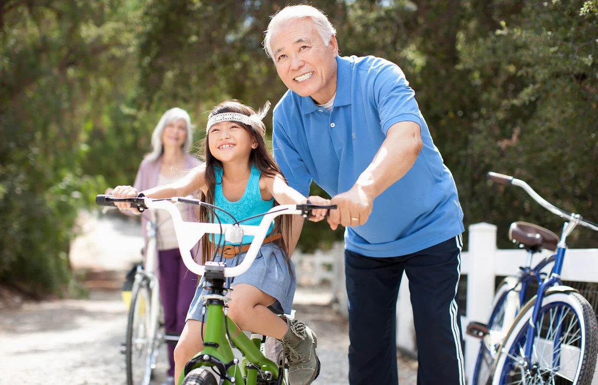 Older man helping granddaughter ride bicycle