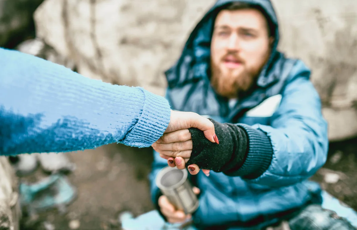 Homeless male on the street getting help from female