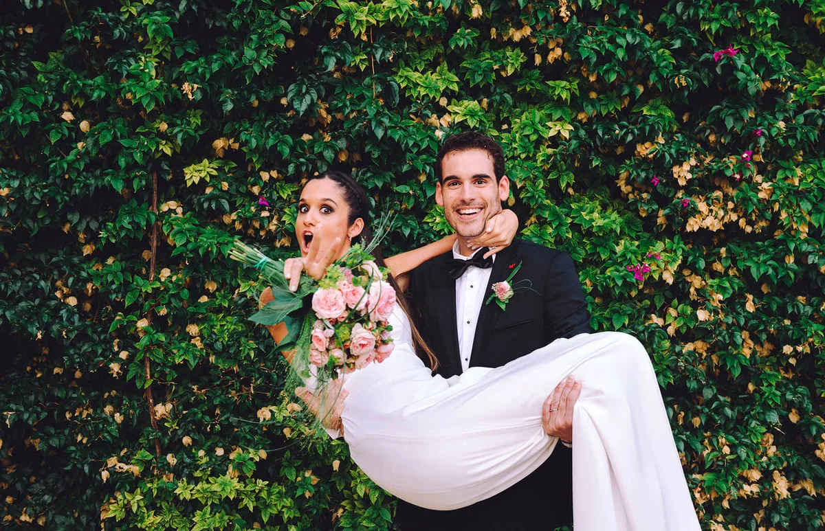 Happy groom holding excited bride in his arms