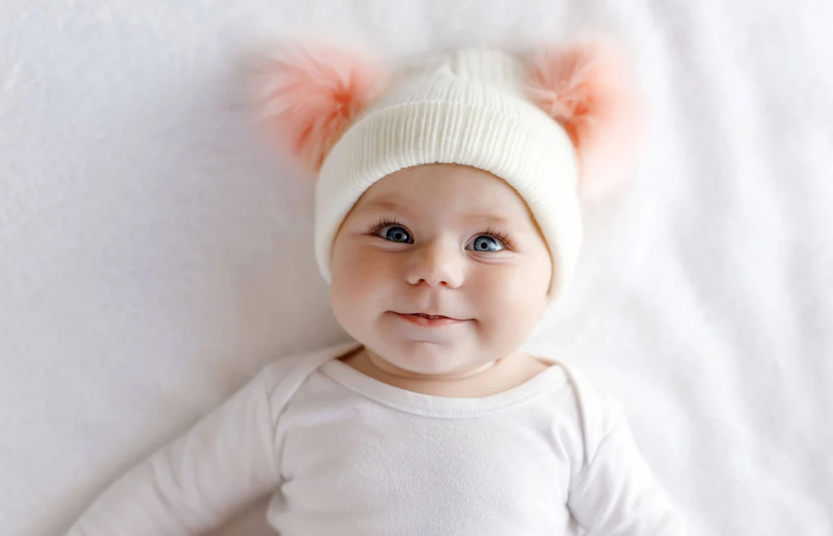 Cute adorable baby child with warm white and pink hat with cute bobbles