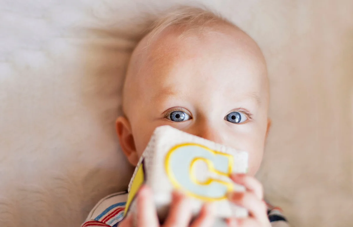 Baby boy holding plush cube with letter 'C' on it