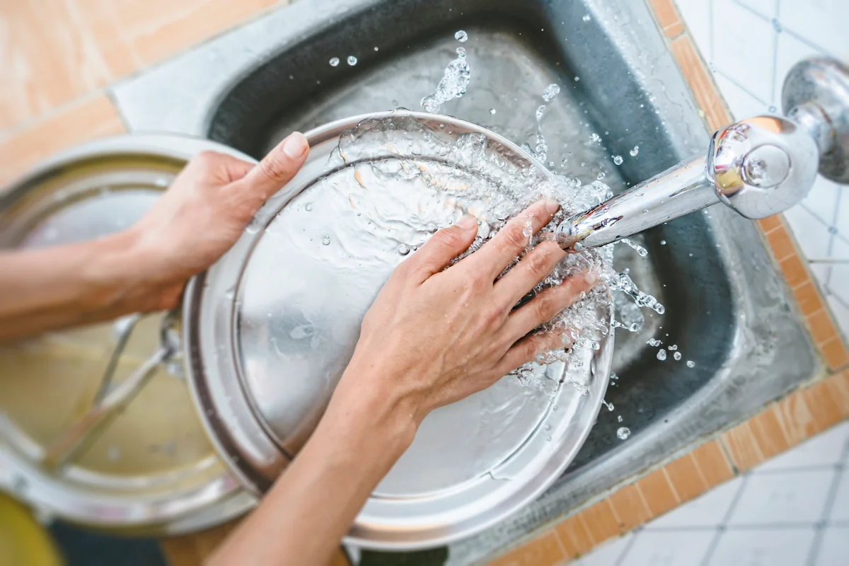 Woman Washing Dishes In Kitchen Sink