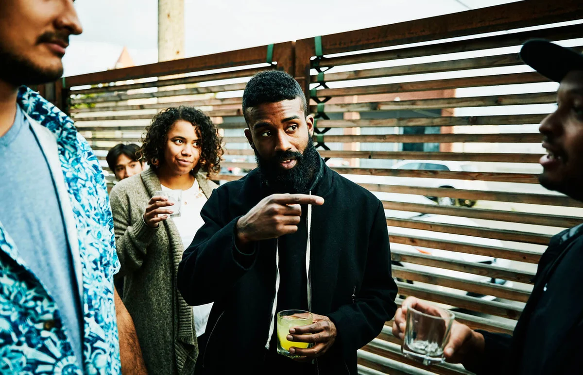 Man in discussion with friends while sharing drinks at outdoor bar